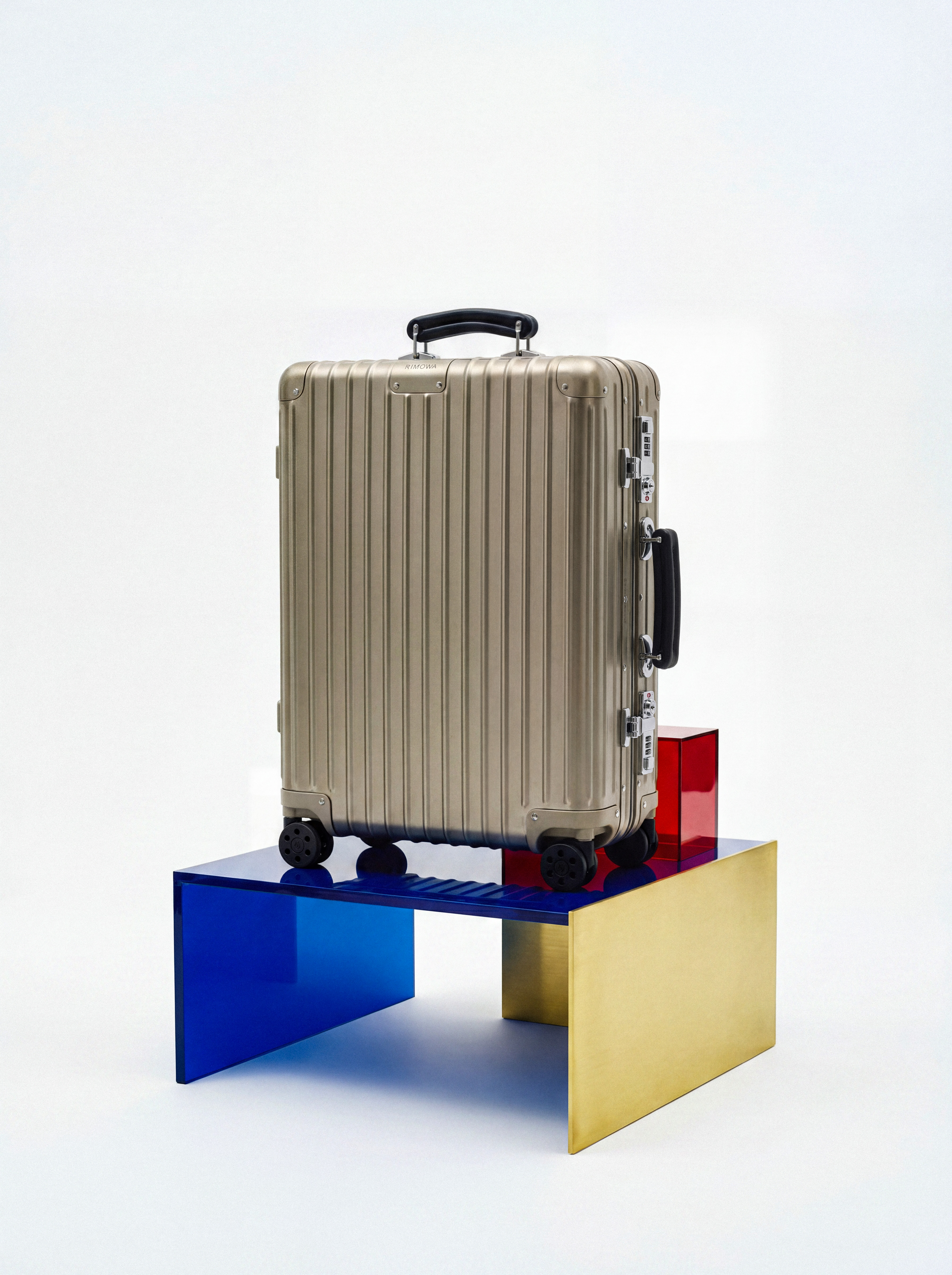 Product still, metallic suitcase on colored plexi blocks