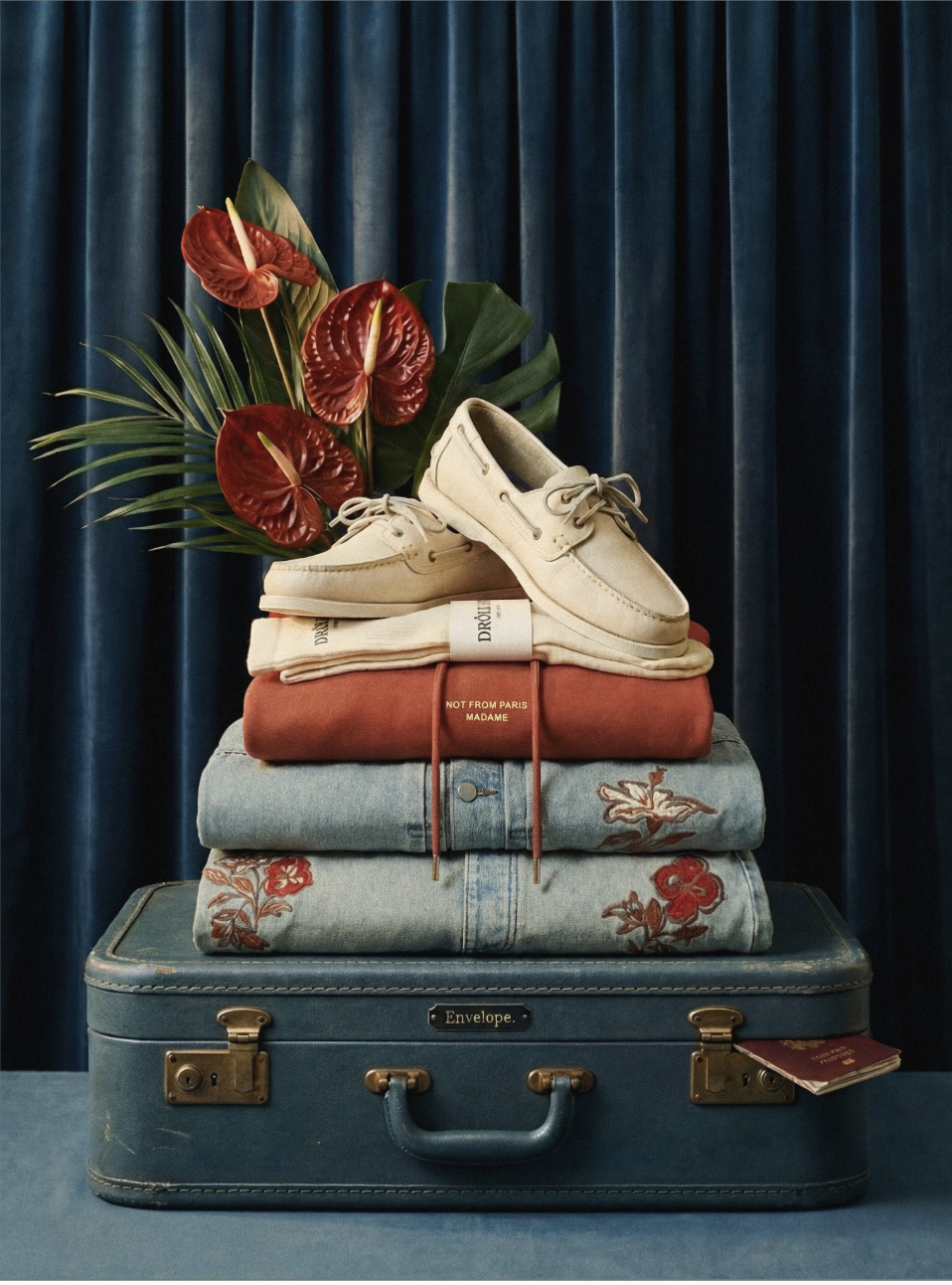 Editorial still life, stacked garments and boat shoes on a suitcase